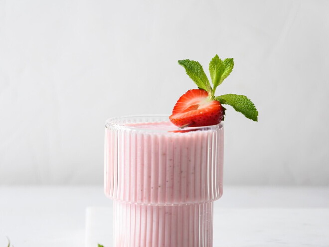 Un vaso contiene batido de fresa y la fruta de decoración