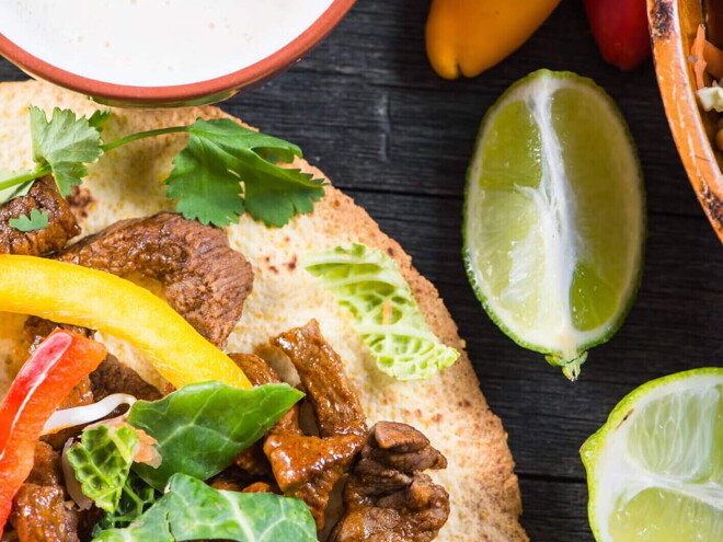 Fajitas rellenas con res y una salsa con limones a un lado