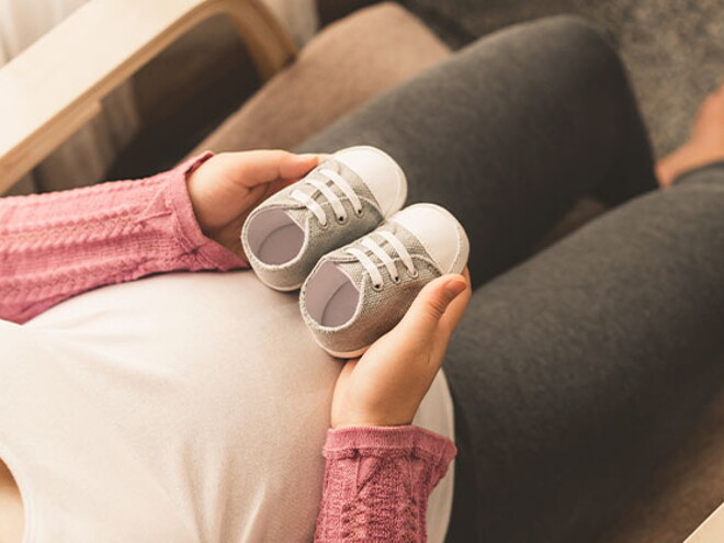 Mamá embarazada de un bebé arcoíris cogiendo unos zapatitos.