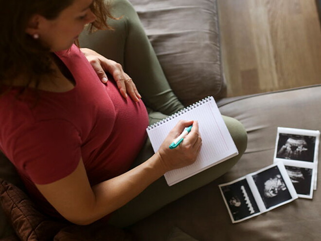 Mamá con un cuaderno mirando la ecografía de su embarazo múltiple.