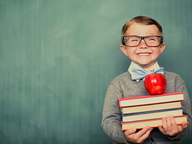 Niño sonriendo con libros en la mano.