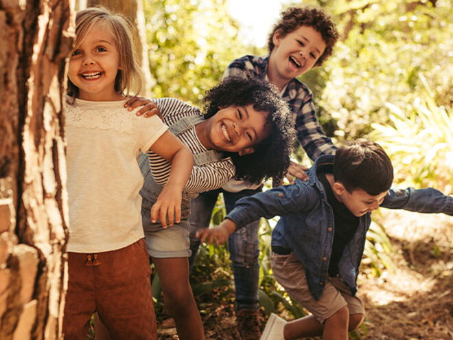 Aprende con Baby and Me la importancia de gestionar las emociones en niños y cómo tu compañía y ayuda es fundamental en este proceso. Niños sonriendo en un parque.