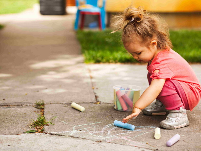 Niña pequeña dibujando en el piso.