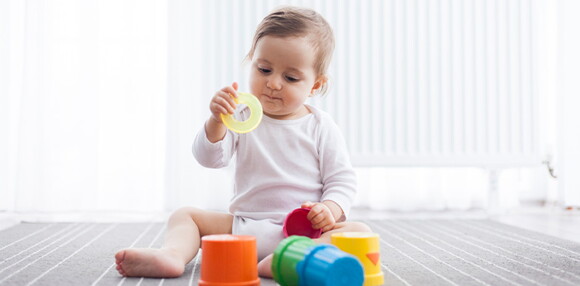 Bebé de 8 meses sentado agarrando sus juguetes