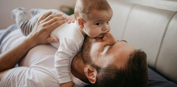 Papá cargando a su bebé de cuatro meses.