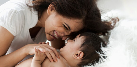 Mamá jugando y sonriendo con su bebé de 8 meses 