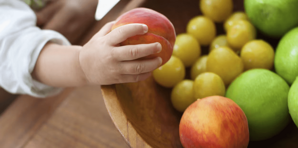 La mano de un niño en primer plano agarrando durazno