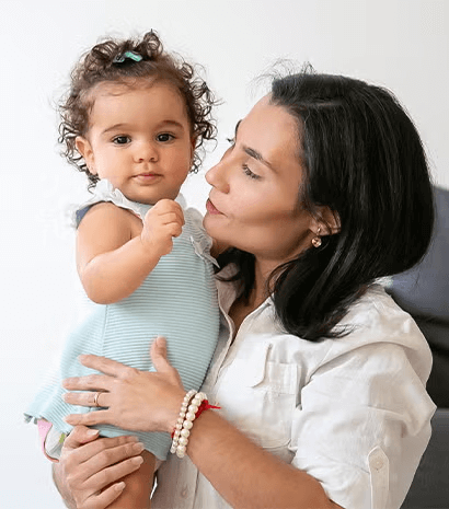 Una madre sosteniendo en brazos a su hija y sonriendo