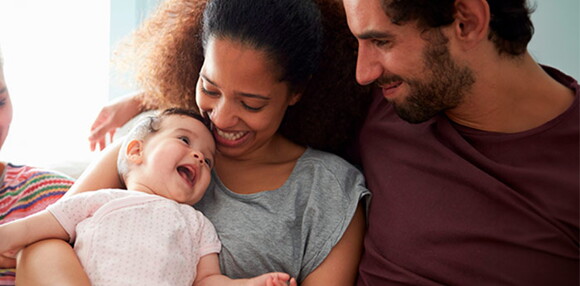 Bebé de 12 meses jugando y sonriendo con sus padres.