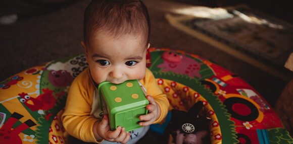 Bebé de 7 meses sentado jugando con sus juguetes