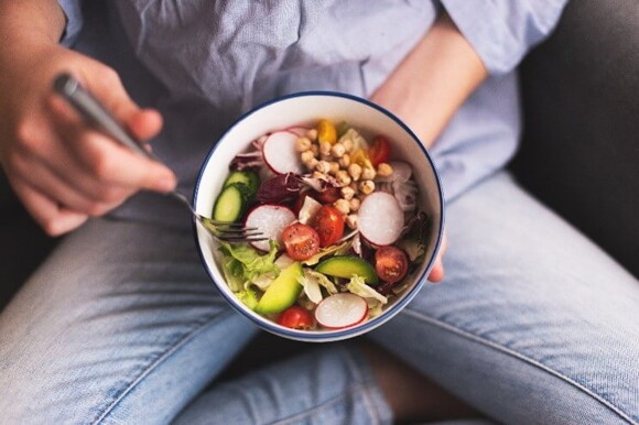 Mujer comiendo vegetales y alimentos ricos en ácido fólico